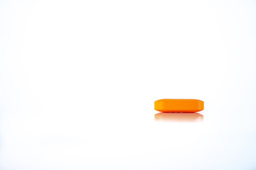 Orange pill on white background. Drug or drug in the form of a tablet