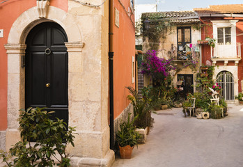 Fototapeta na wymiar Terracotta walls and potplants in a tiny courtyard on Ortigia Island, Syracuse, Sicily, Italy
