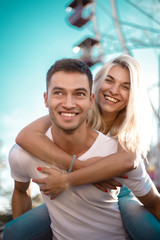 Obraz premium Happy young cheerful loving couple walking outdoors in the amusement park having fun.