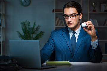 Young employee with golf ball in office