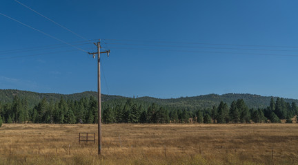 electric post with wires crossing farm