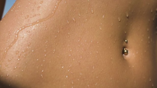 Wet body, swimsuit girl. A young woman wearing a red bikini drips with water during a summer day.