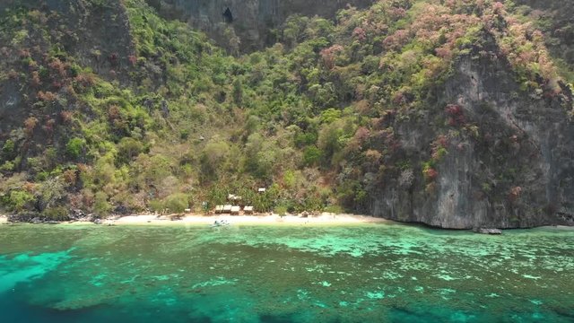 Aerial drone shot flying over clear, shallow, blue water and towards a paraw boat at a secret beach, at Coron island, in Philippines, Asia