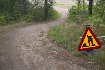 Construction site sign beside a road going down