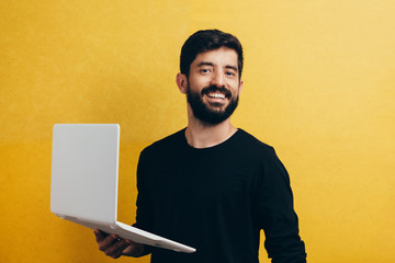 Young man with laptop on color background. Studio portrait.