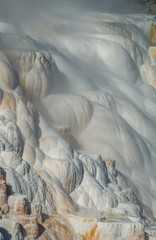 Steam rises from white and gold mounds of crystallized calcium carbonate in a vertical image from...
