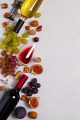 Glass and bottle of wine with grapes, figs and nuts on white stone texture background. View from above, top studio shot