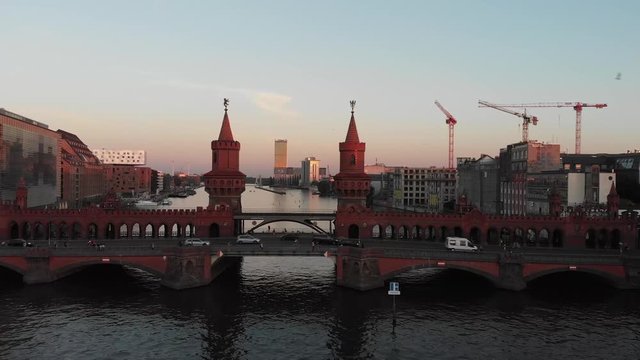Aerial panoramic view of the Oberbaum Bridge in Berlin, Germany with drone flying over the Spree River during the sunset