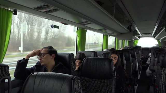 A wide shot of the flixxbus, with all kind of tired passengers, driving in the early morning.