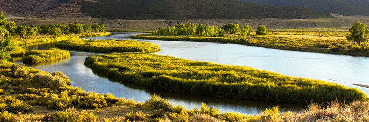 Panorama of the Green River as it flows through Browns Park National Wildlife Refuge, a wild, beautiful, remote area of mountains, prairies, and wetlands in the extreme northwest corner of Colorado - obrazy, fototapety, plakaty
