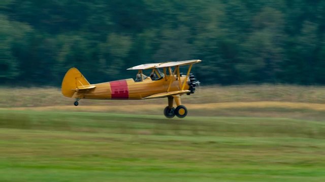 Fast motion cinemagraph of Stearman biplane taking off set against a forest.