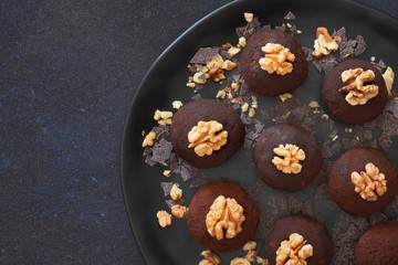 Flat lay of dark plate of rum balls with wallnuts on dark background