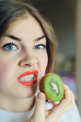portrait of blonde young woman with sliced kiwi fruit, parody of beautiful glamorous girls or...