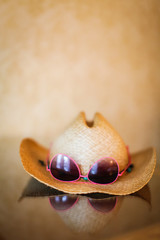 summer cowboy Woven hat and sunglasses with reflection on glass table