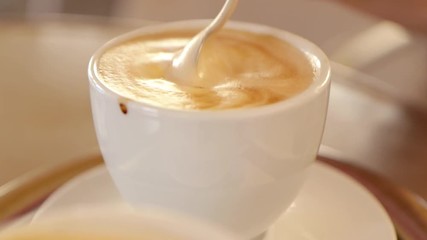 Close up shot of a creamy coffee being stirred in a small white cup