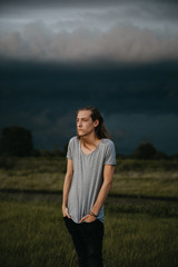 Obraz premium Attractive Young Male Model with Man Bun and Long Blonde Hair Posing for Camera Outside in Filed During Sunset