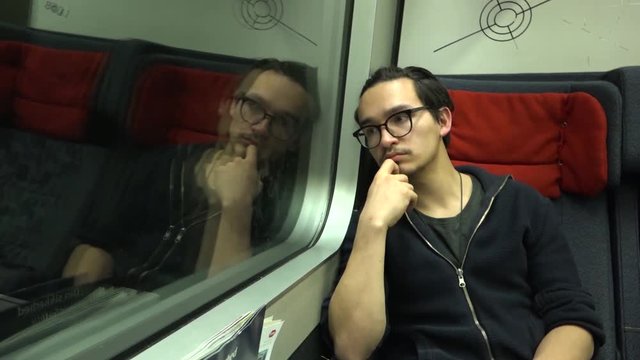 A young man looking out of the window of a Danish train at night.