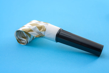 Festive props and party accessories concept with a party blower or noisemaker isolated on blue...