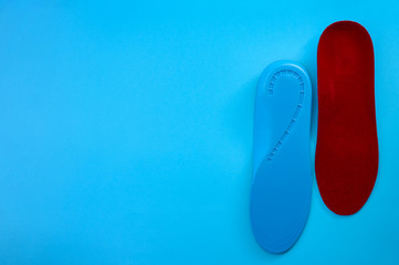 Foot support and healthy feet concept with orthopedic shoe insoles isolated on blue background with copy space