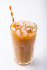 Ice coffee in a tall glass with cream poured over and coffee beans. Cold summer drink on white background