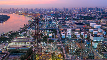 Aerial view petrochemical industrial oil refinery at sunset with city background.