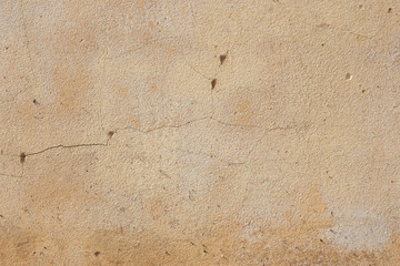 Pale brown weathered external concrete wall as background with interesting crack textures