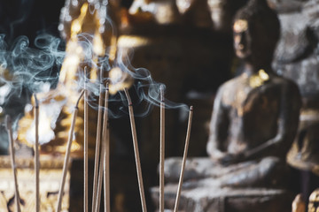 Des bâtons d& 39 encens brûlent devant un autel avec des figurines de Bouddha, mise au point sélective