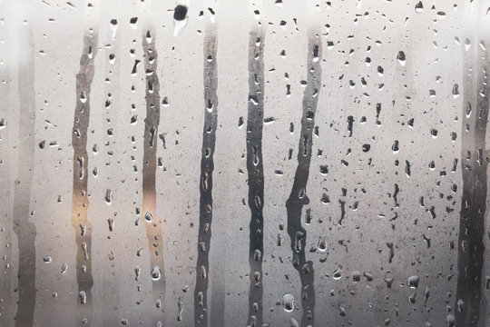 Wet, steamy glass windows with gray steam and water droplets as background