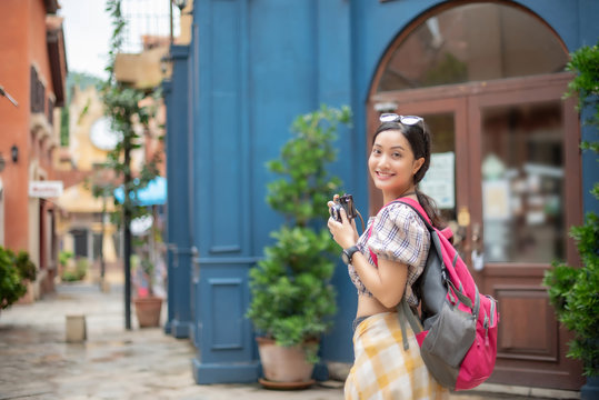 Young Asian women backpacks have fun with shopping  and happy are taking photo at outdoor mall/supermarket/market in the evening; Attractive young woman spend time together.