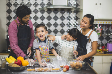 Happy family father and mother teaching cute girl and little boy preparing making Wheat flour  and Make a fruit cake healthy at kitchen for the first time. first lesson and healthy lifestyle concept.