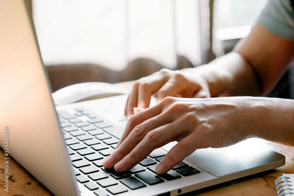 Poster closeup image of hands working and typing on laptop keyboard in front of the window in soft light