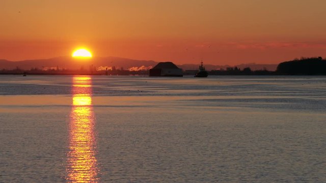 Tug and Barge Sunrise 4K UHD. A tugboat towing a barge on the Fraser River near Steveston at sunrise. Vancouver, British Columbia, Canada. 4K. UHD. Slow motion.
