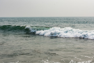 Yarada beach with indian ocean waves crashing onto the shore rocks and stones. Long exposure shot with silky smooth water and rock in the background.