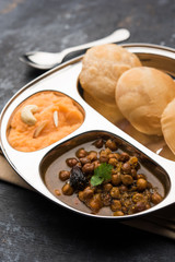 Suji/Sooji Halwa Puri or Shira Poori with black chana masala breakfast, served in a plate and bowl. selective focus