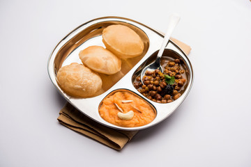 Suji/Sooji Halwa Puri or Shira Poori with black chana masala breakfast, served in a plate and bowl. selective focus