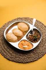 Suji/Sooji Halwa Puri or Shira Poori with black chana masala breakfast, served in a plate and bowl. selective focus