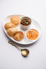 Suji/Sooji Halwa Puri or Shira Poori with black chana masala breakfast, served in a plate and bowl. selective focus