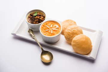 Suji/Sooji Halwa Puri or Shira Poori with black chana masala breakfast, served in a plate and bowl. selective focus
