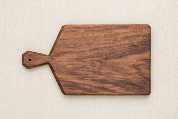 Handmade black walnut chopping board on burlap, walnut texture background