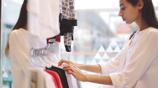 young girl looking and chooses clothes in the store