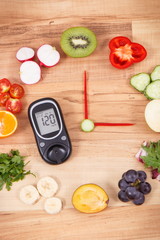 Glucometer with sugar level and clock made of fruits with vegetables, healthy lifestyle of diabetics concept