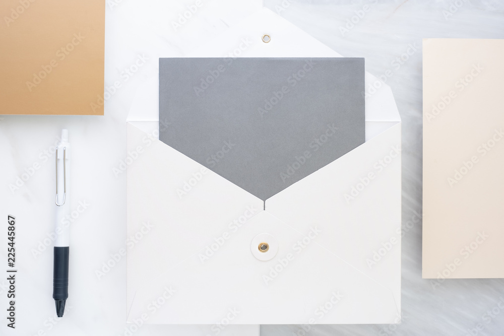 Poster Top view of blank grey card in white envelop with pine leaf on two layer step of marble table top.Mock up template for display of design.modern business items.