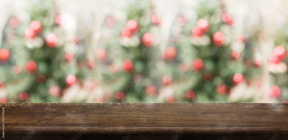 Poster Empty rustic wood table top with abstract blur christmas tree red decor ball and snow fall background with bokeh light,winter Holiday backdrop,Mock up banner for display of product or promotion.