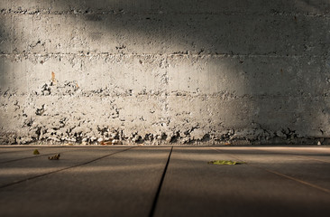 Low angle view perspective of wooden floor to blur grunge concrete wall with sunlight.Blank space...