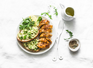 Baked chicken breast and avocado toast-healthy lunch on a light background, top view
