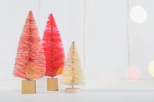 Miniature Christmas trees on a white wooden background