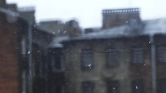 Seasonal snowfall in city. Close-up snowflakes flying against the background of an old shebby facade. Typical residential buildings St. Petersburg, Russian Federation. Slowmotion footage