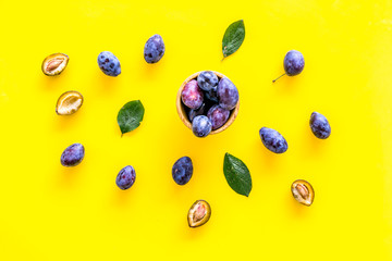 Blue plum for dessert. Purple plum and leaves pattern on yellow background top view copy space