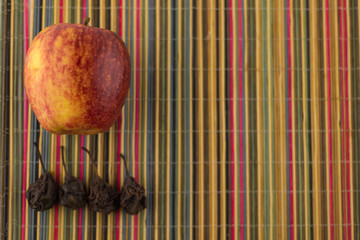 ripe red Apple and dried pear on the colorful Mat made of bamboo