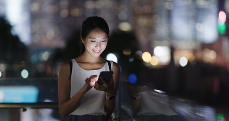 Woman use of mobile phone in city at night